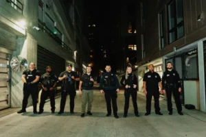 Professional security team standing in formation in an urban alley at night, demonstrating readiness and coordinated protection services.